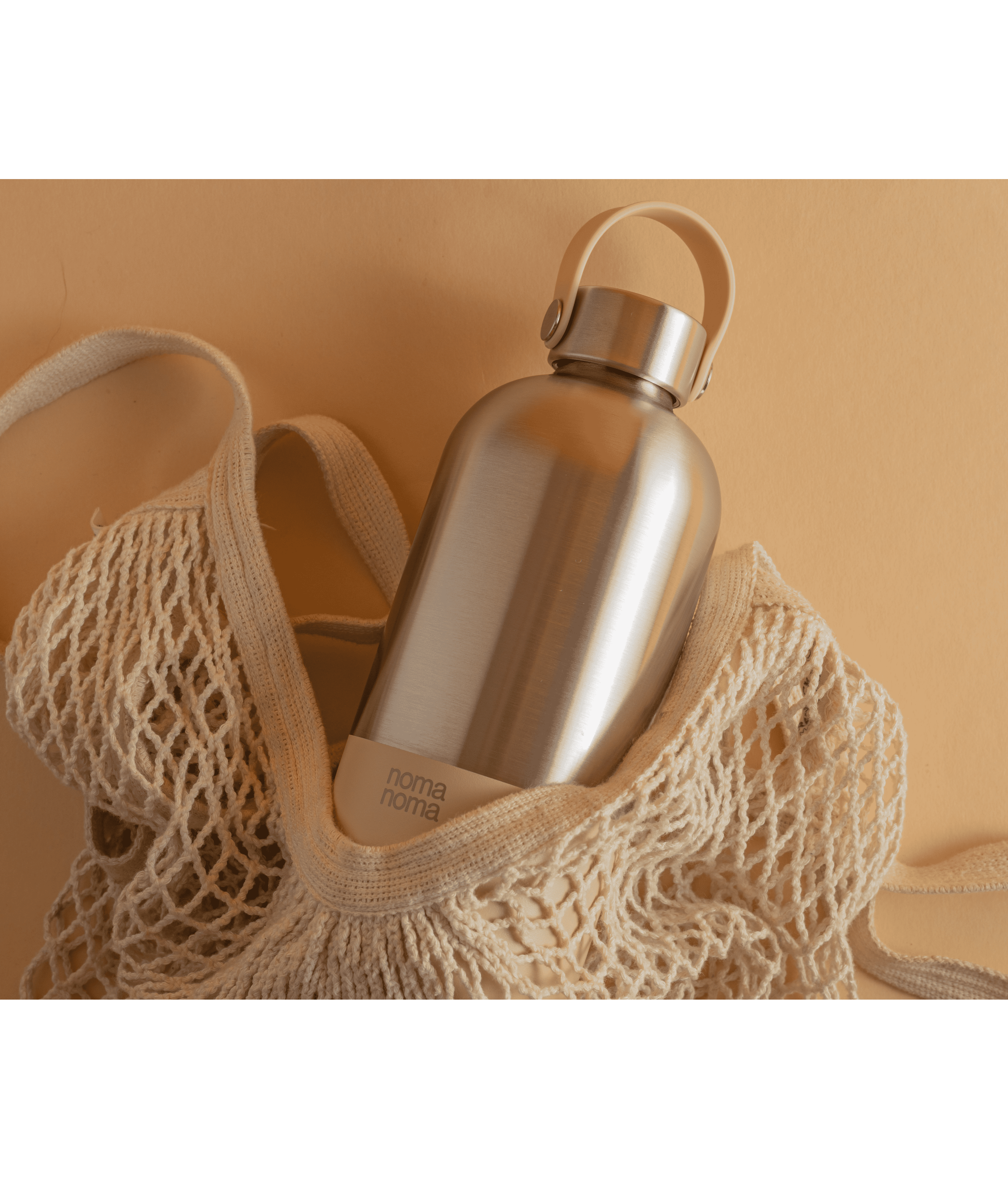 Eine noma noma Edelstahl Trinkflasche in beige liegt in einem Jutebeutel.