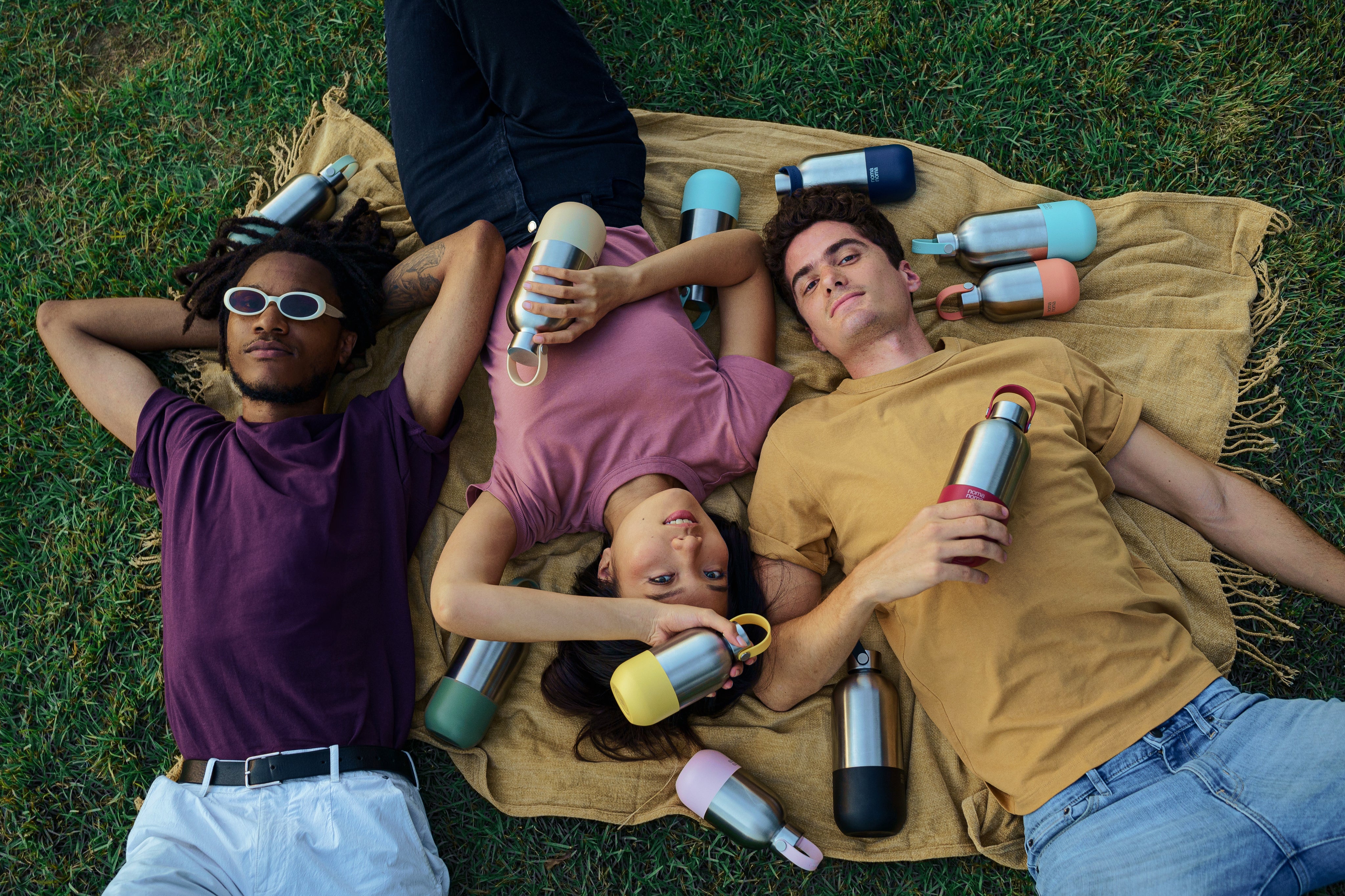 Das noma noma Model Team chillt auf einer Decke mit jeder Menge unserer Edelstahl Trinkflaschen