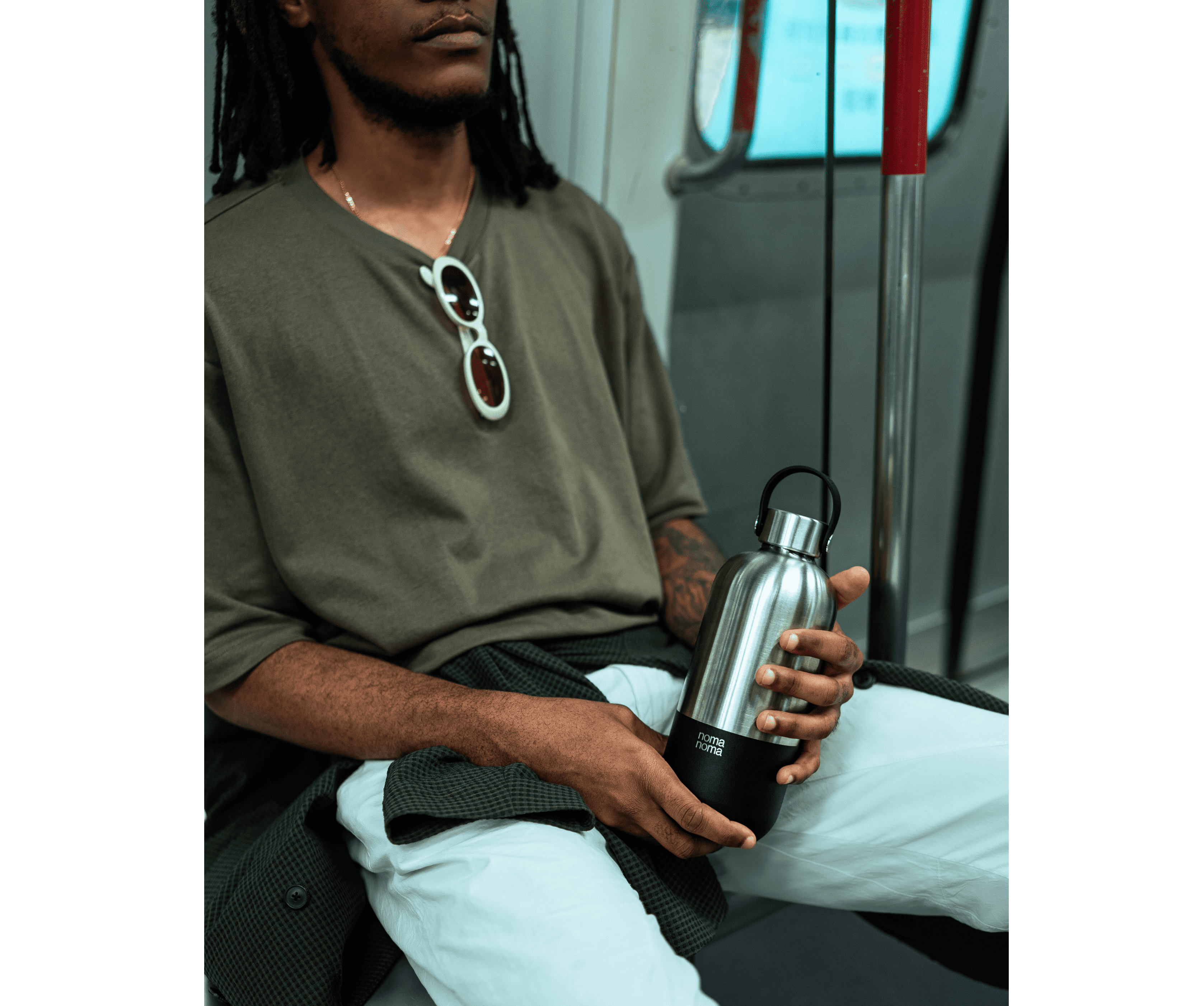Ein Mann sitzt in der U-Bahn und hält die noma noma 750ml Isolierflasche in coffee black. 