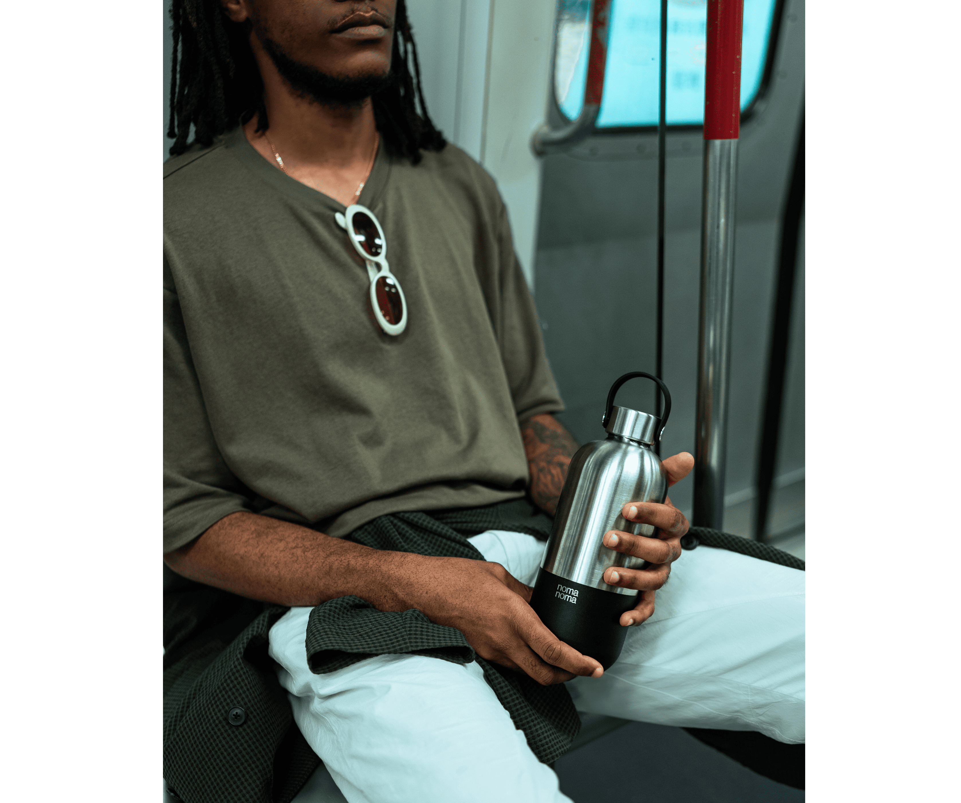 Ein Mann sitzt in der U-Bahn und hält die noma noma 750ml Isolierflasche in coffee black.