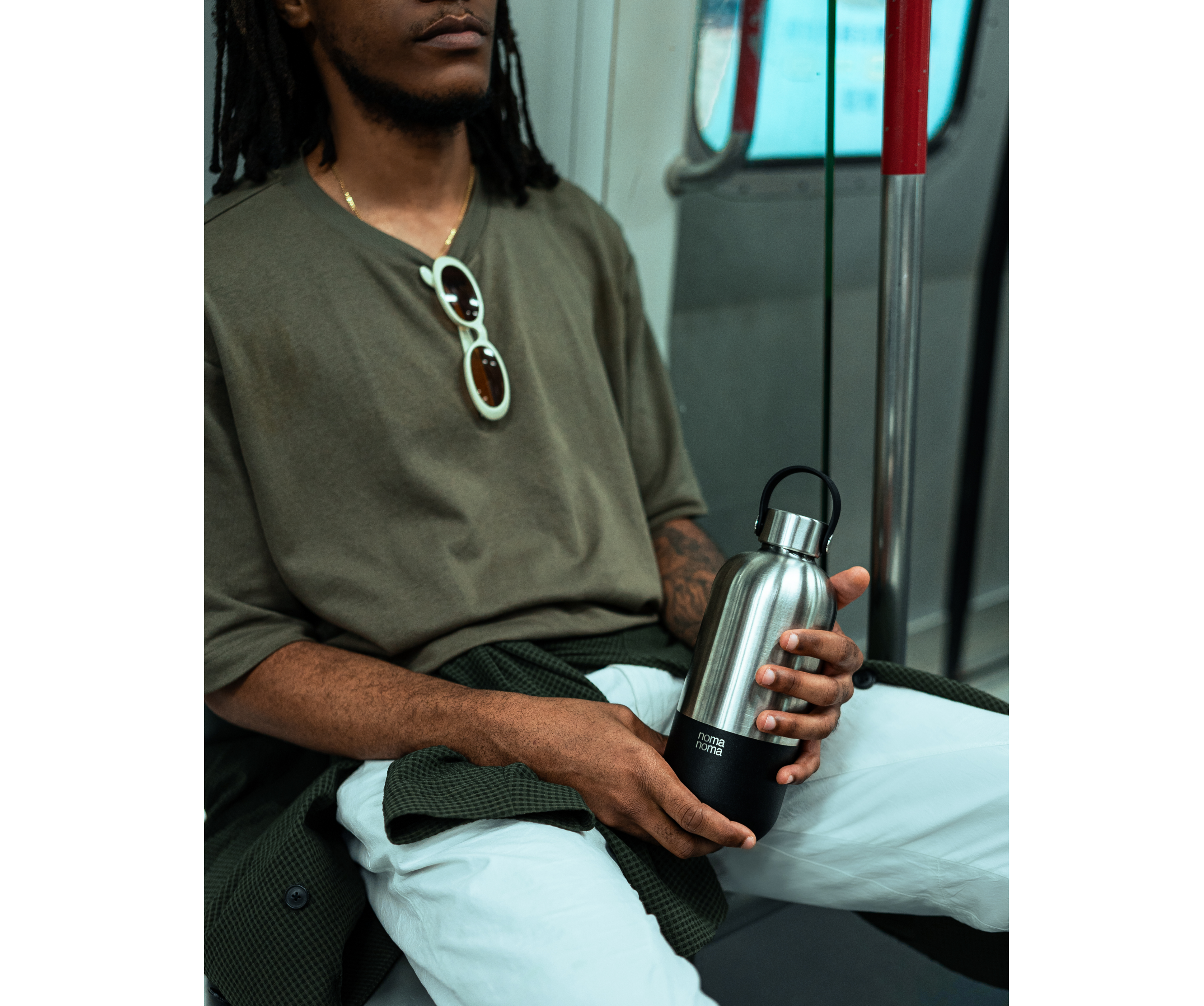 Ein Mann sitzt in der U-Bahn und hält die noma noma 750ml Isolierflasche in coffee black. 